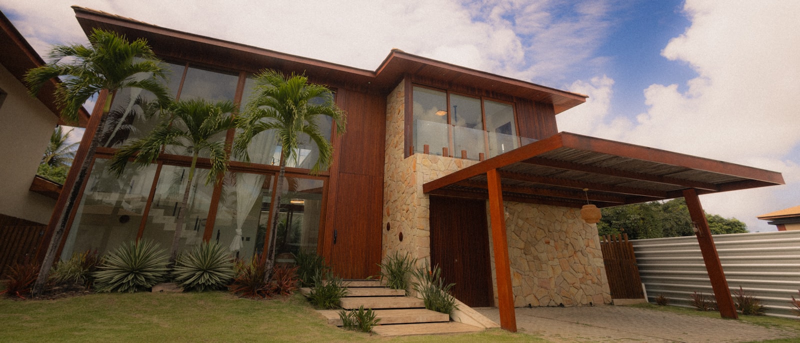 Casa contemporânea com fachada de madeira e pedra em estilo campo brasileiro
