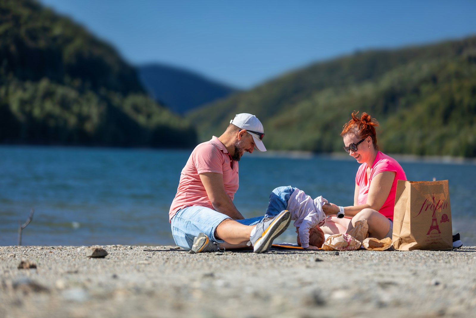 Família relaxando à beira de lago em dia ensolarado